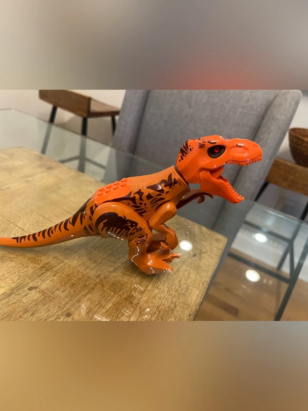 orange-and-brown molded plastic Tyrannosaurus Rex dinosaur makes noise building